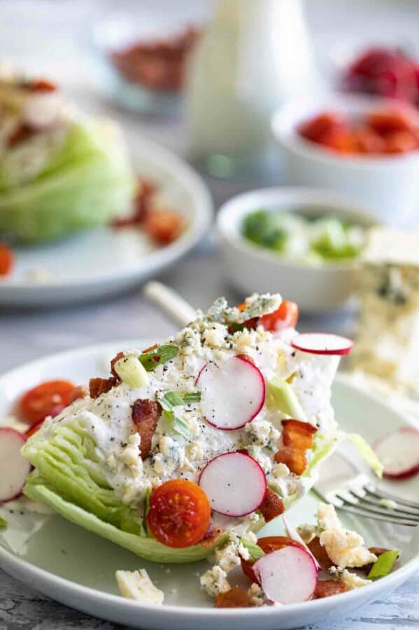 wedge salad on a plate with tomatoes, radishes and bacon