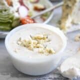 bowl of homemade blue cheese dressing with a salad in the background