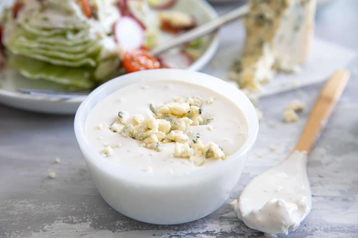 bowl of homemade blue cheese dressing with a salad in the background