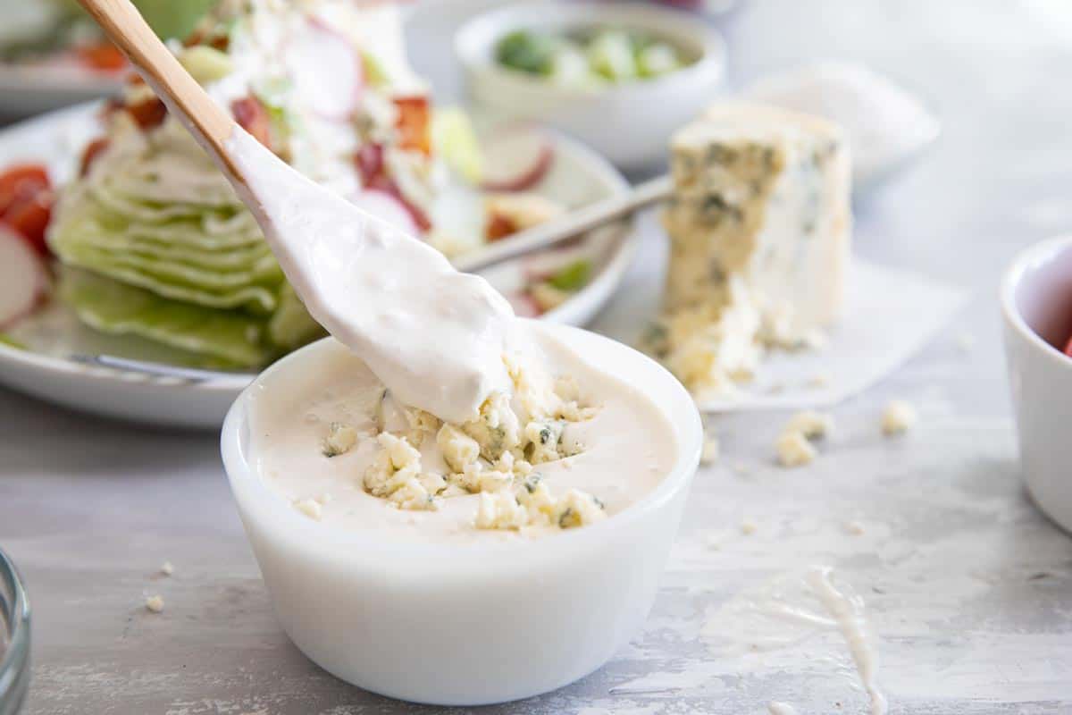 taking a spoonful of blue cheese dressing from a small bowl
