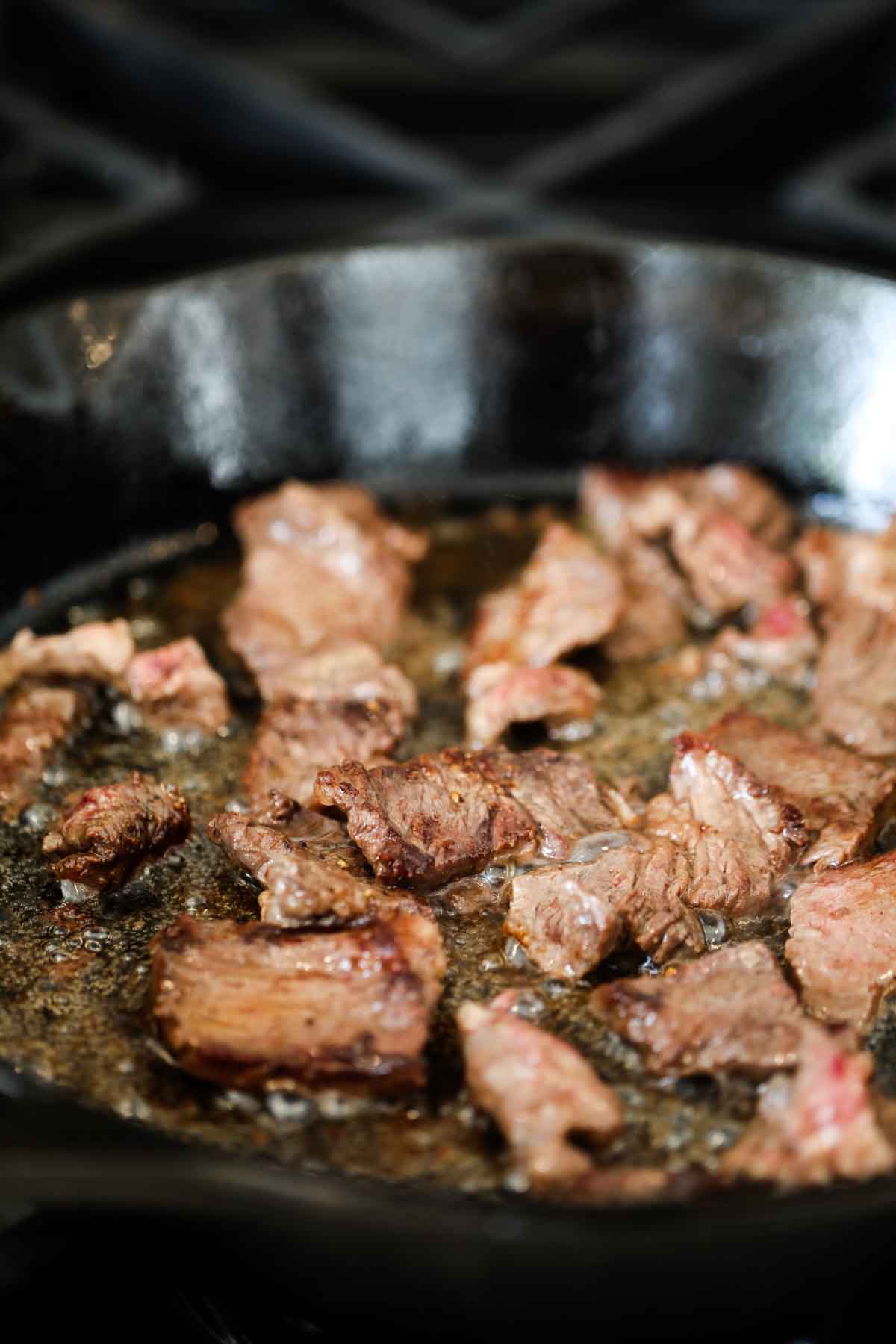 beef tips cooking in a cast iron pan