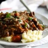beef tips and gravy over mashed potatoes on a plate