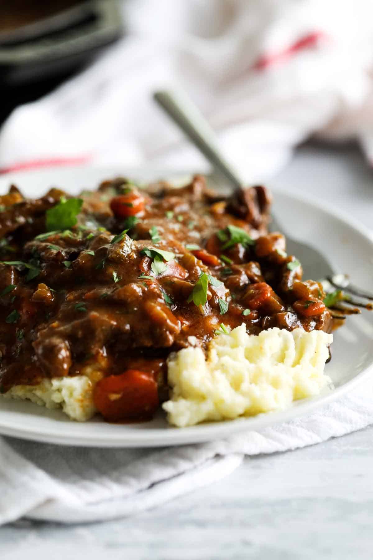 beef tips and gravy over mashed potatoes on a plate