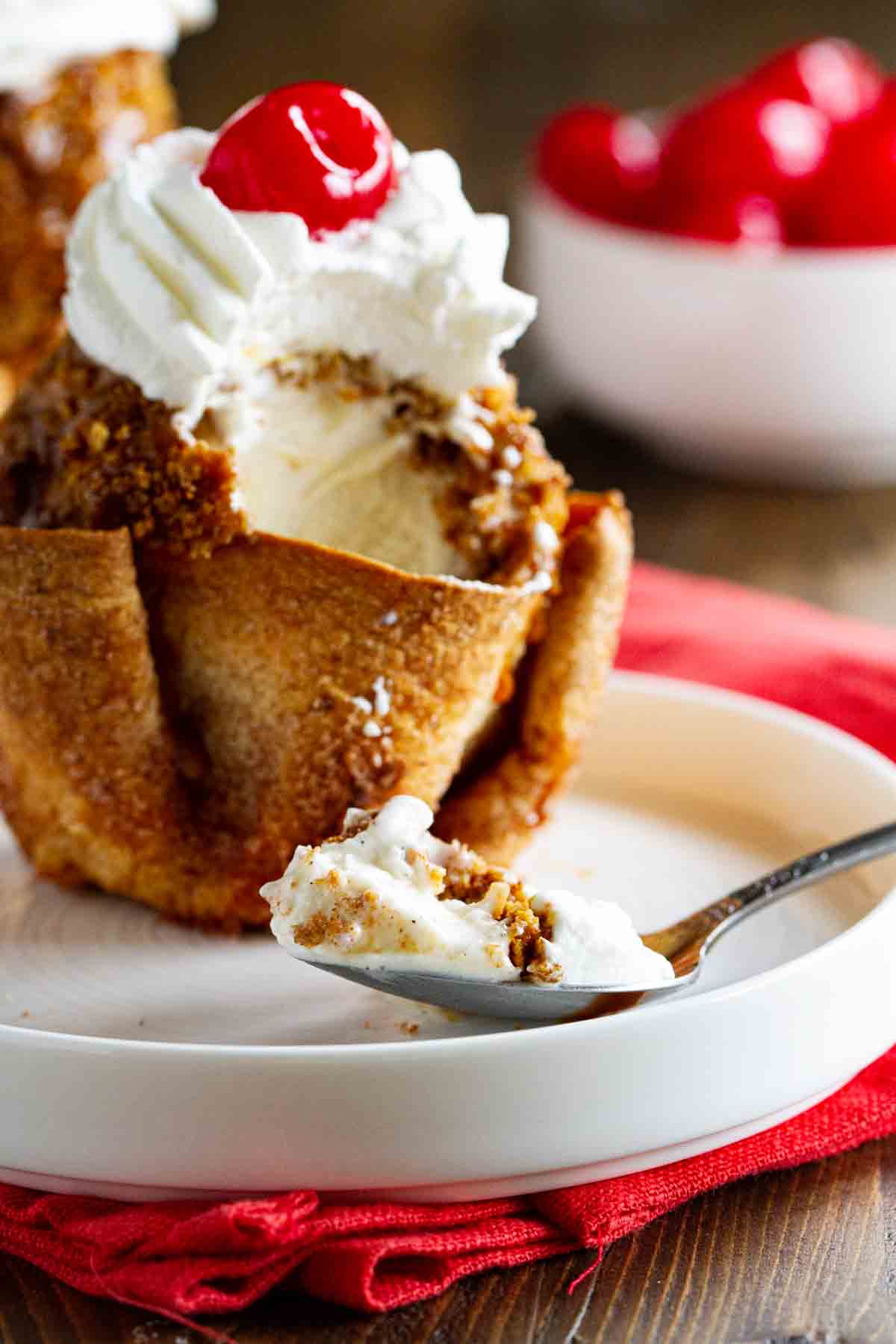 Finish off any Mexican-inspired meal with this Fried Ice Cream Recipe that is served in cinnamon and sugar coated tortilla bowls. Crunchy on the outside, creamy on the inside - this is a dessert you won’t be able to stop talking about. fried ice cream with bite of ice cream on a spoon