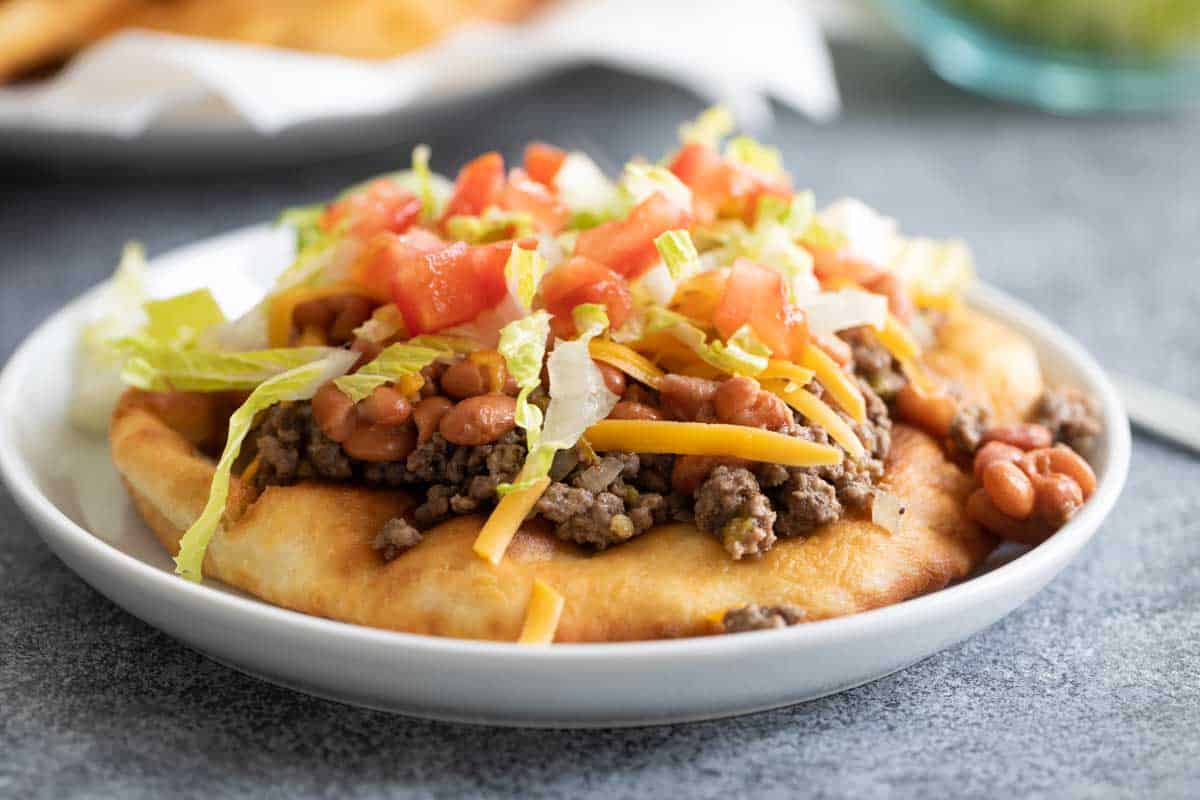 Fry bread topped with ground beef, beans and toppings for a Navajo tao
