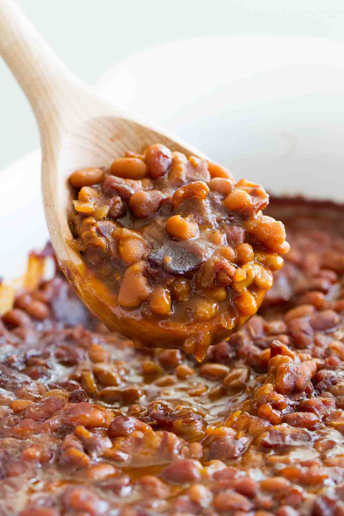 scoop of baked beans with a wooden spoon