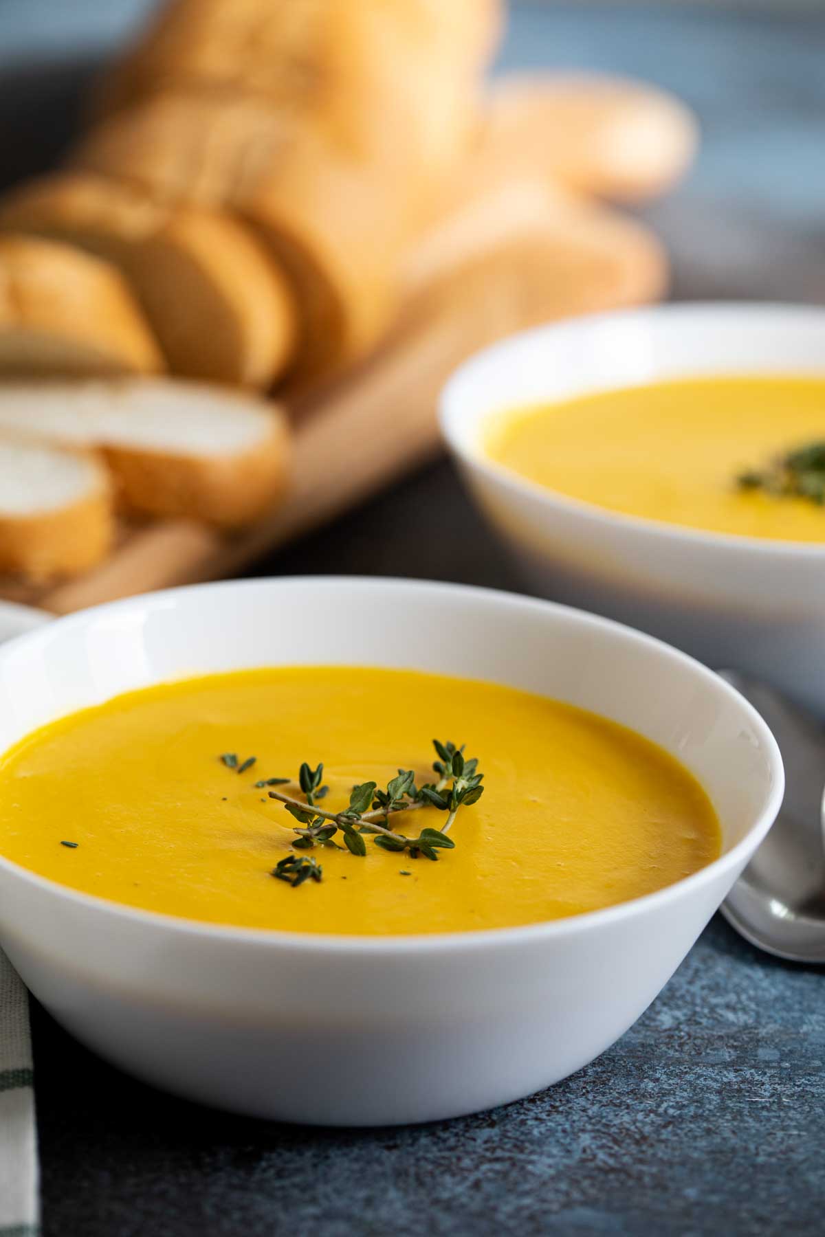 butternut squash soup topped with fresh thyme in a bowl