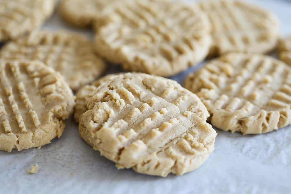A classic that everyone loves, these Peanut Butter Cookies are soft and easy to make. They make the perfect after school snack! peanut butter cookies stacked on parchment paper