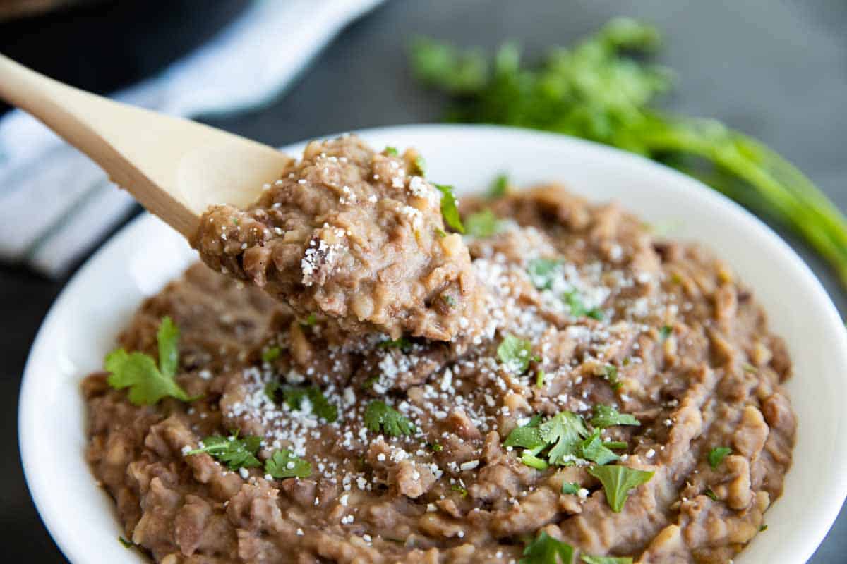 bowl of homemade refried beans with a wooden spoon