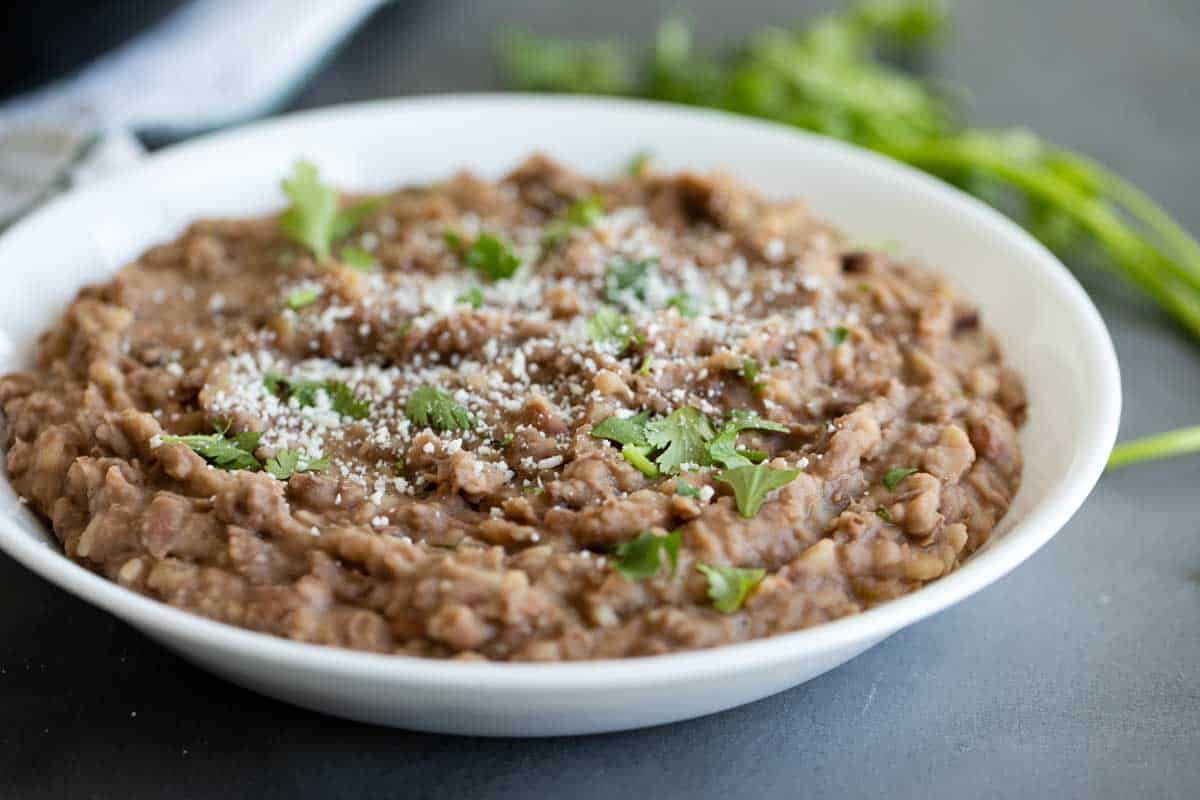 bowl full of refried beans topped with cilantro and cotija cheese