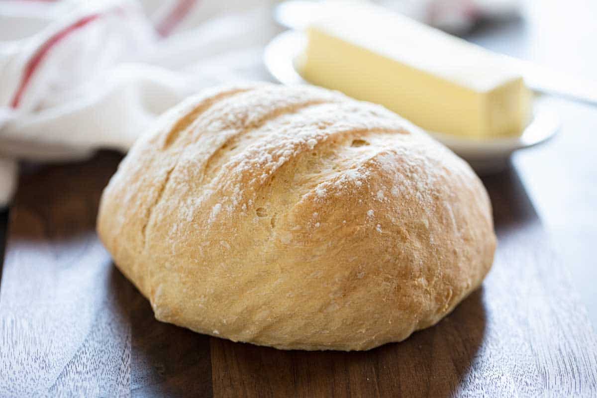 loaf of no knead artisan bread with butter in the background