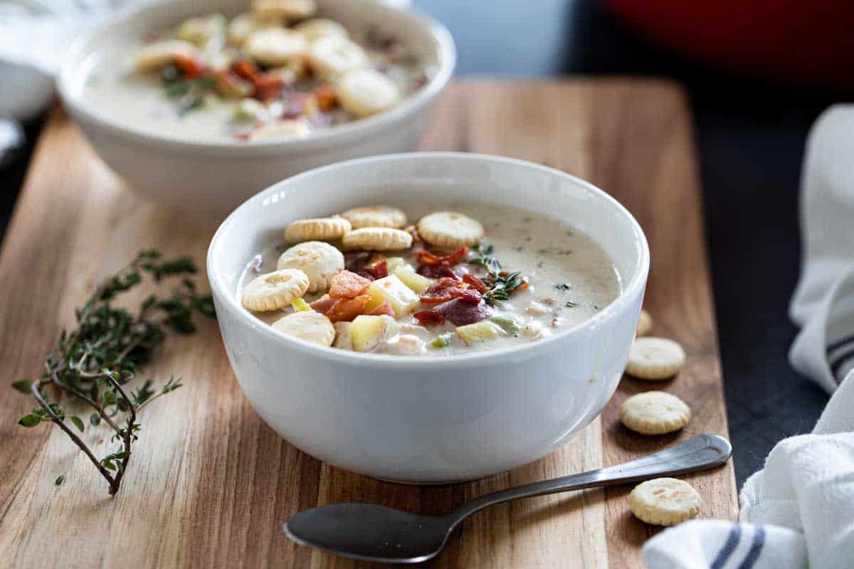 bowl of clam chowder topped with crackers and bacon