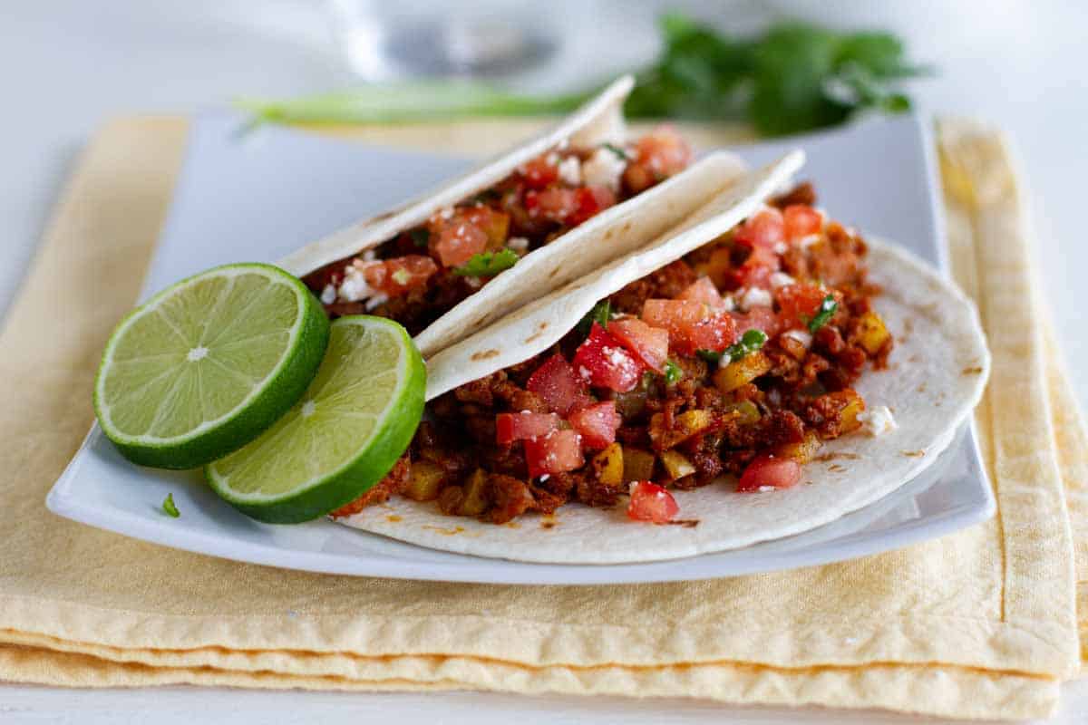 Potato Tacos with Sausage on a plate with slices of lime