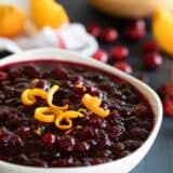 white bowl filled with fresh cranberry sauce topped with strips of orange zest