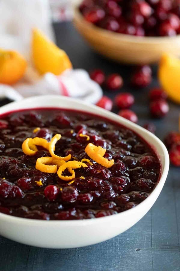 white bowl filled with fresh cranberry sauce topped with strips of orange zest