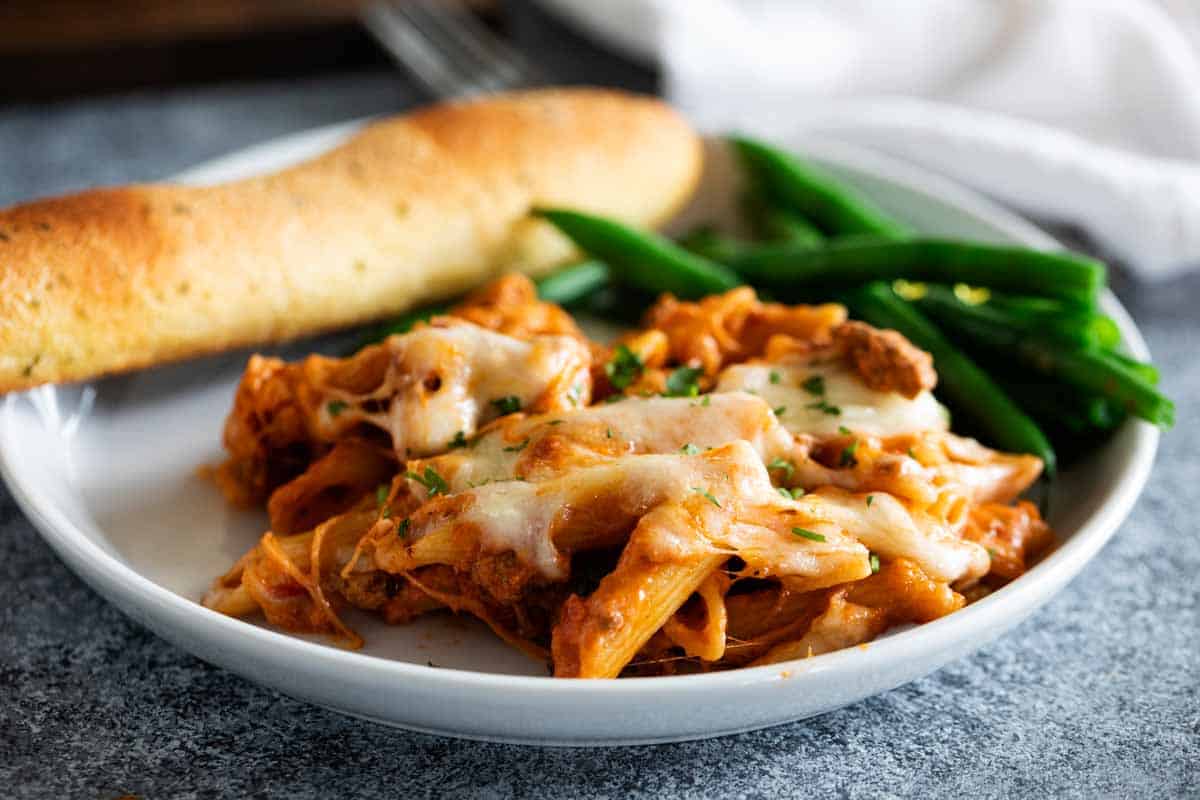 plate with penne pasta bake, green beans and breadstick