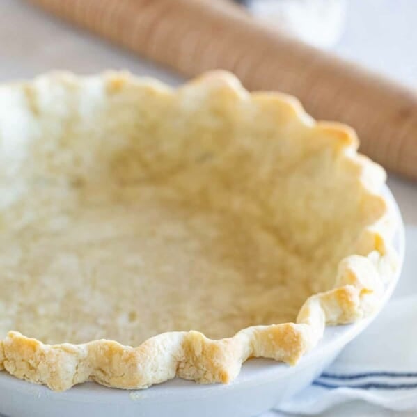 baked pie crust in a dish with a rolling pin