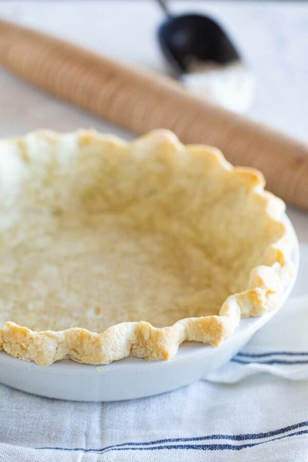 baked pie crust in a dish with a rolling pin