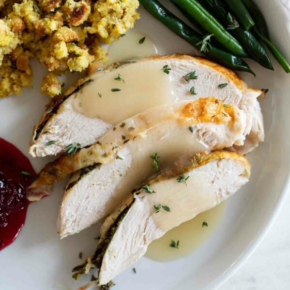 overhead view of sliced turkey on a plate with green beans and stuffing