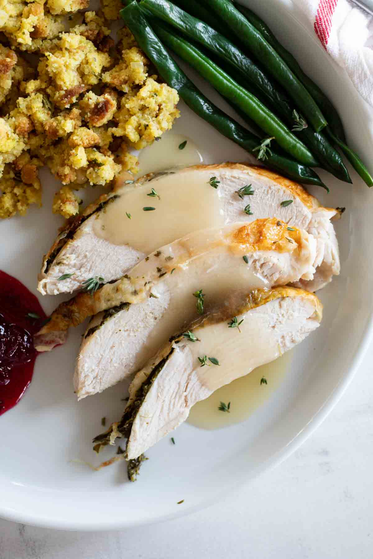 overhead view of sliced turkey on a plate with green beans and stuffing