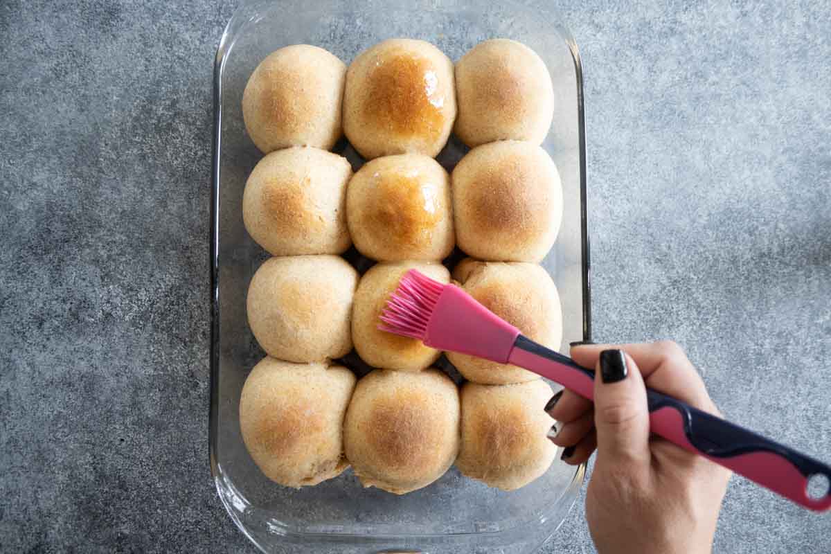 brushing butter on top of whole wheat rolls