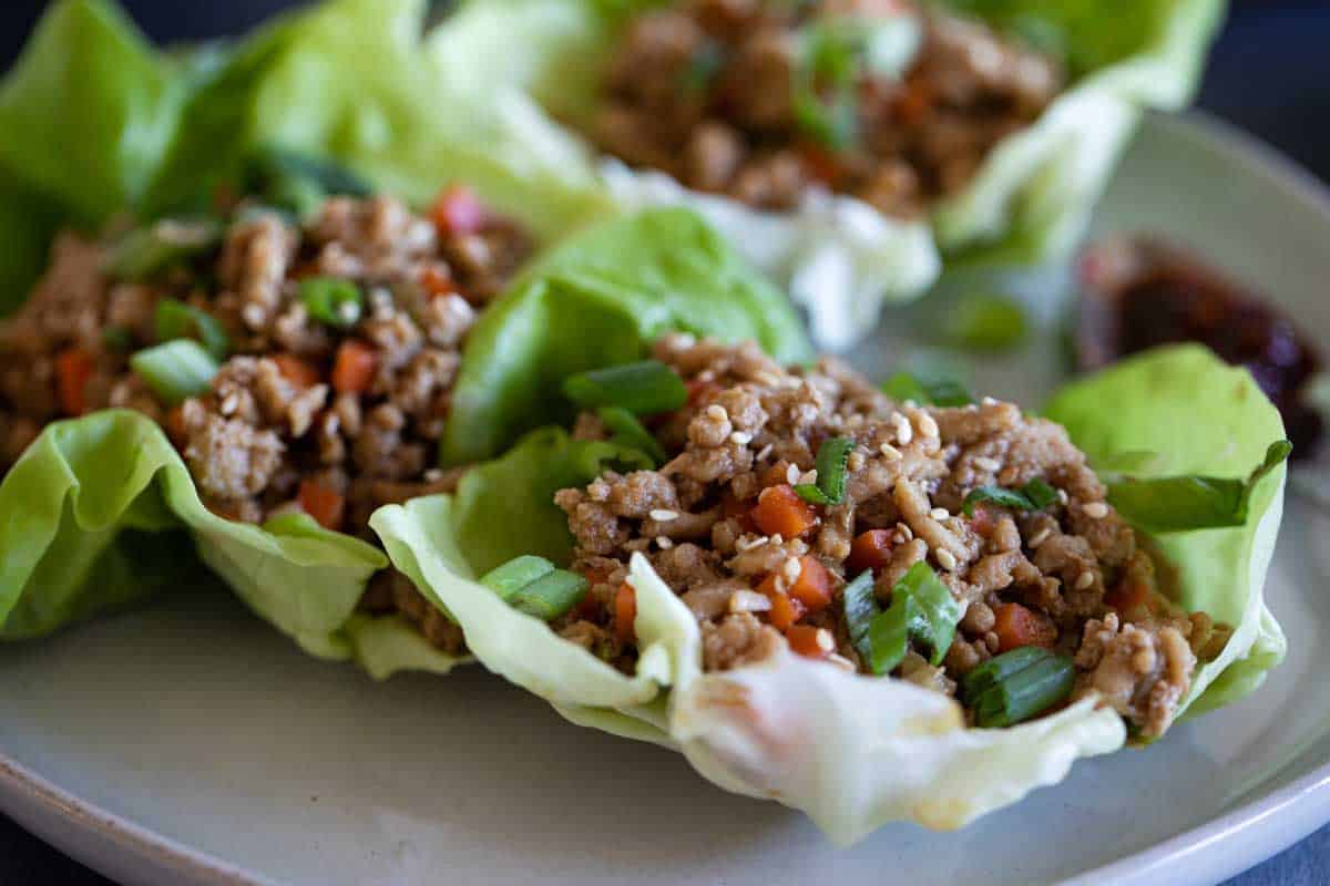 chicken lettuce wraps on a plate topped with green onions
