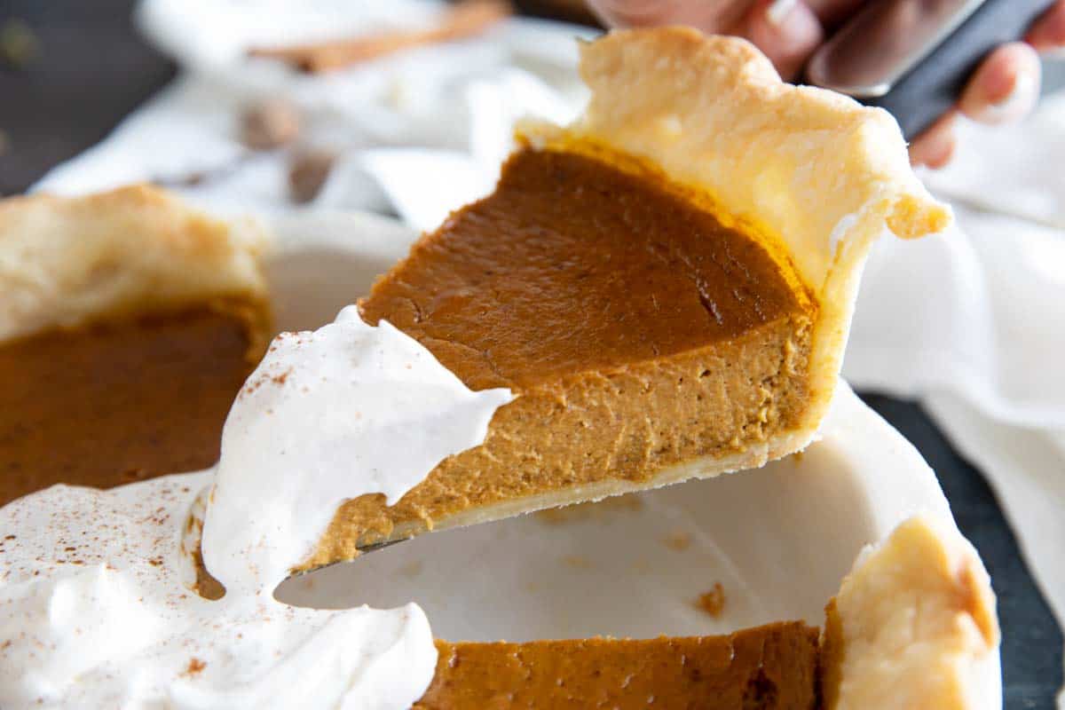 slice of pumpkin pie being taken from a pie dish