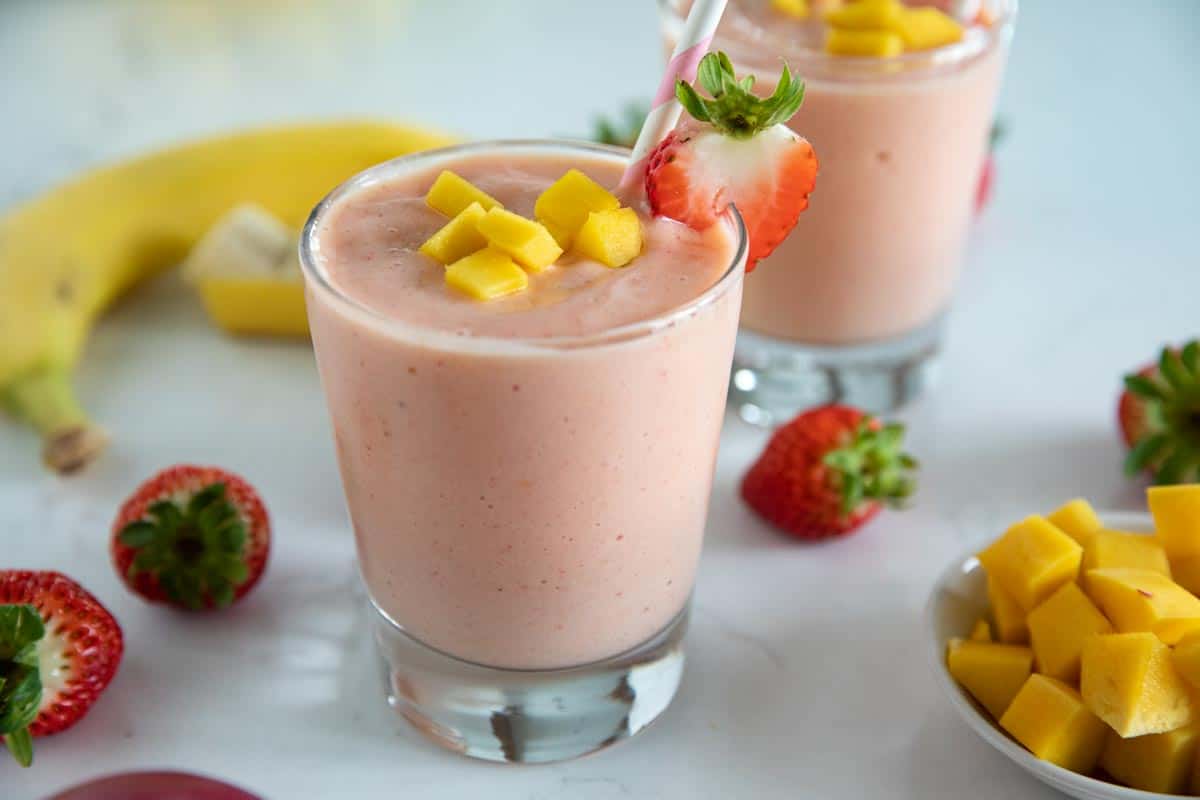 two cups of tropical smoothie topped with fresh fruit