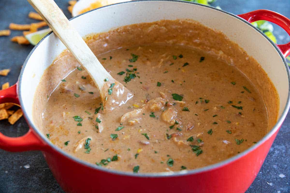 dutch oven with chicken enchilada soup and a wooden spoon