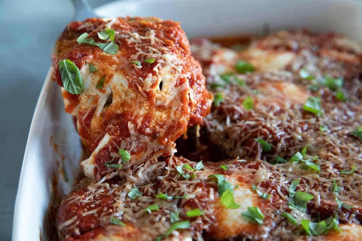 eggplant parmesan being taken out of a casserole dish with a scoop.