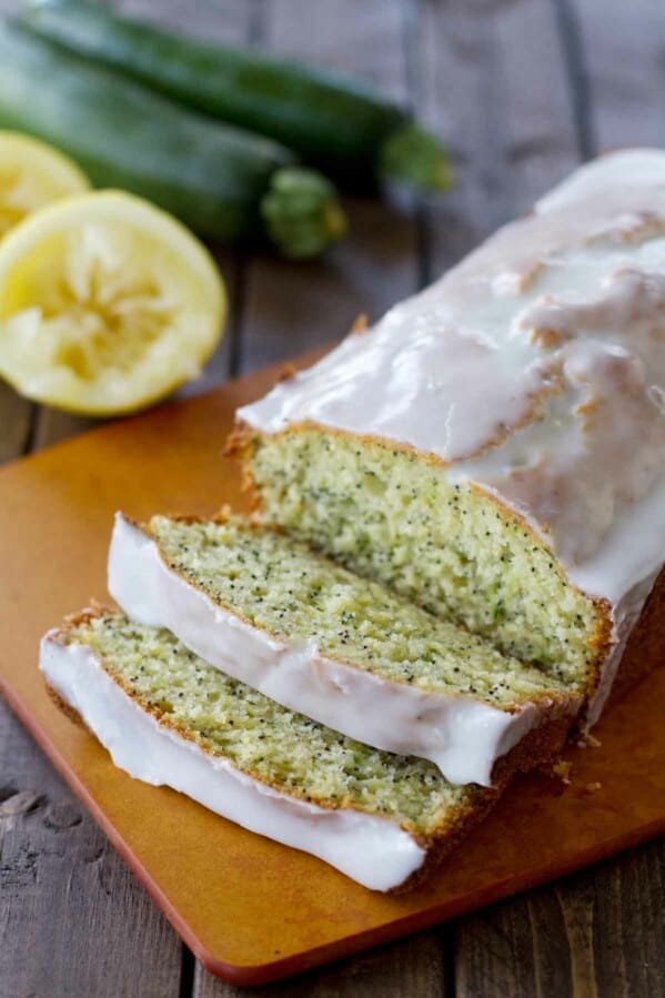 loaf of lemon poppy seed zucchini bread on a cutting board with the first slices cut.