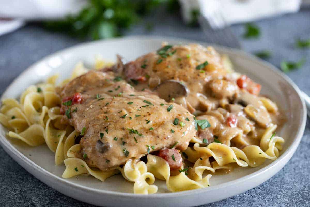 plate with mustard chicken served over buttered egg noodles