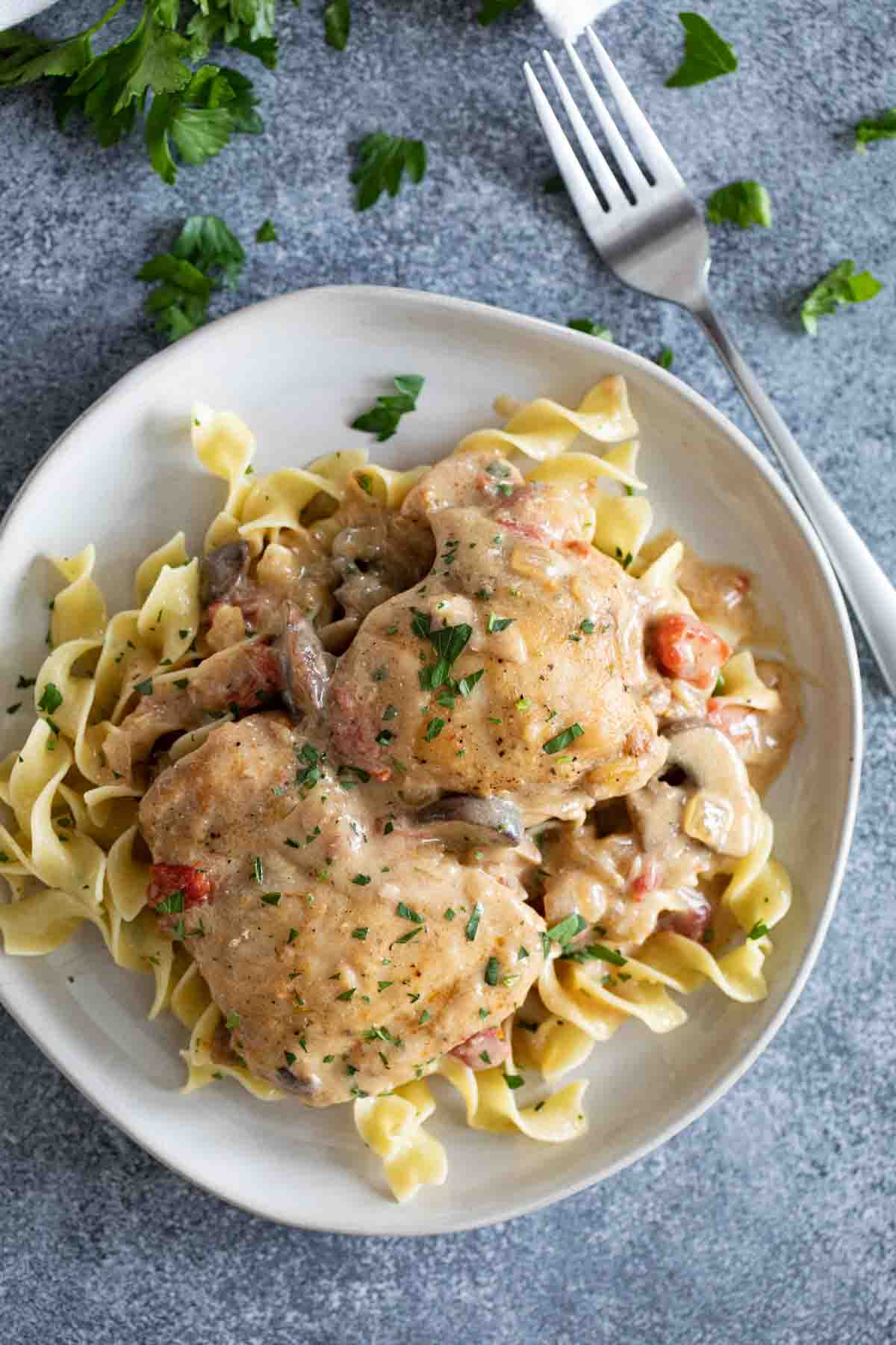 overhead view of a plate with buttered noodles topped with mustard chicken