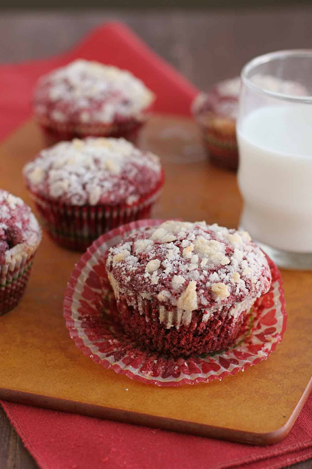 red velvet muffins on a board with a glass of milk.