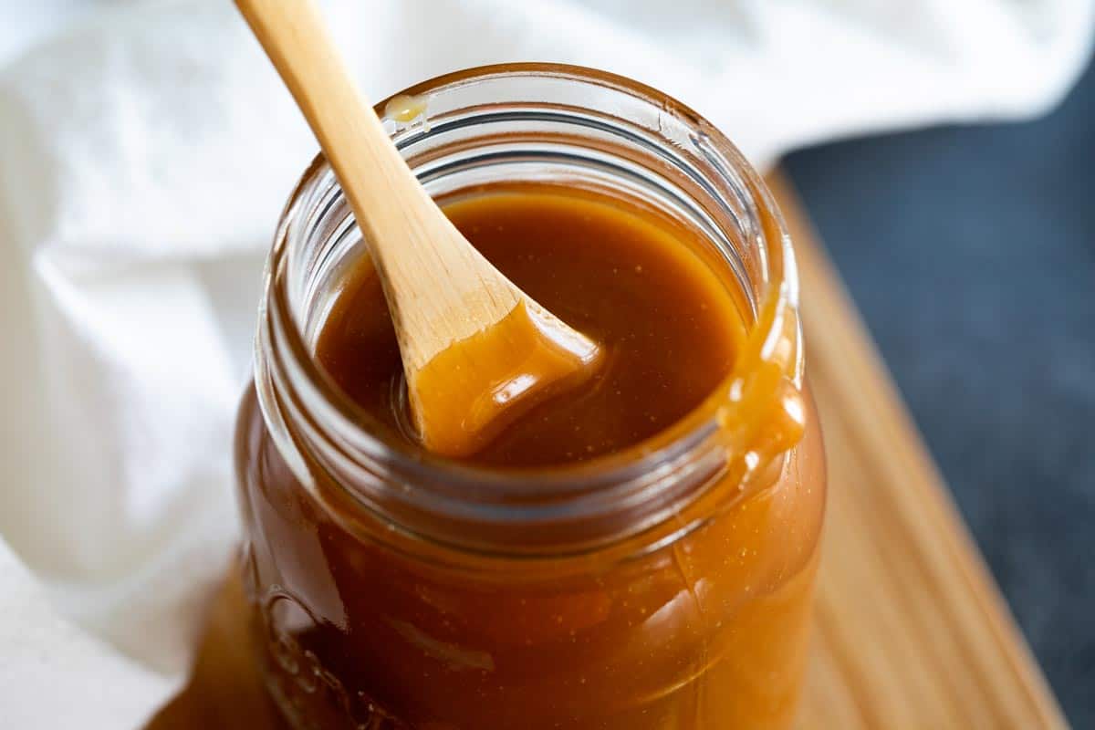 view of salted caramel in a jar with a wooden spoon.