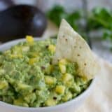 Bowl filled with Tropical Guacamole with a tortilla chip.