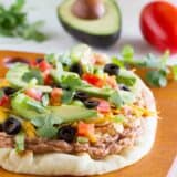 7 layer flatbread on a cutting board with ingredients in the background