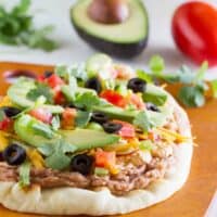 7 layer flatbread on a cutting board with ingredients in the background