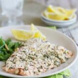 salmon fillet coated with almonds and herbs on a plate with lemon slices