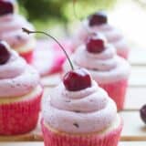 Almond cupcakes topped with fresh cherry frosting with a fresh cherry on top