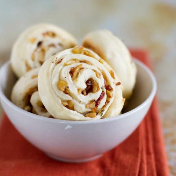 apple bacon pinwheels in a small bowl on a cloth napkin
