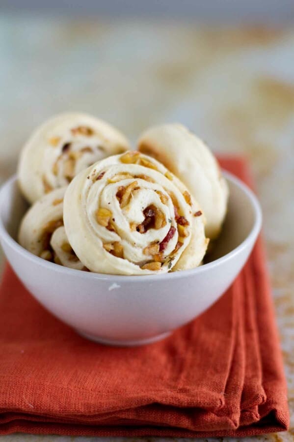 apple bacon pinwheels in a small bowl on a cloth napkin