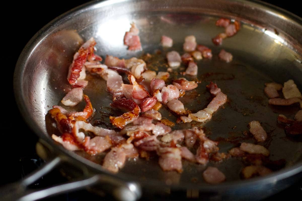 bacon pieces cooking in a skillet