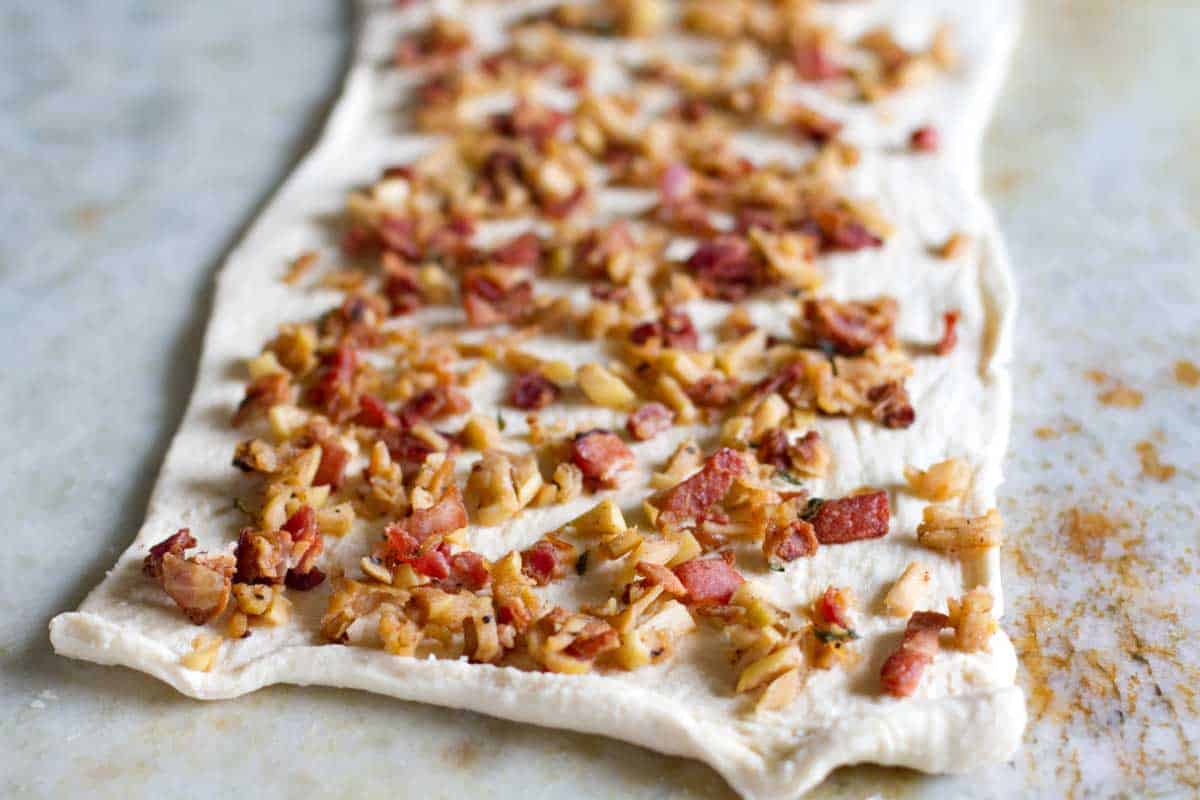 cooked bacon and apples on top of crescent dough