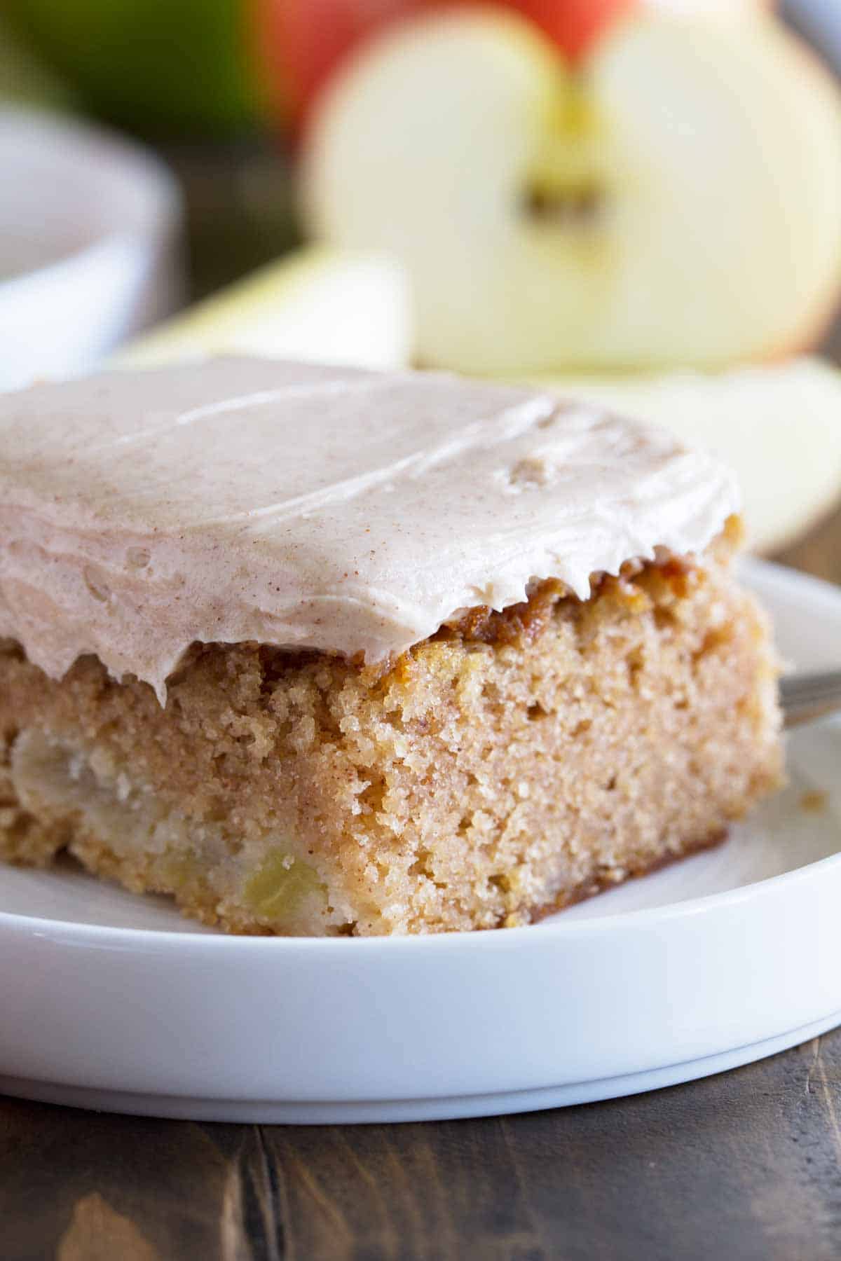 The perfect, no-fuss fall dessert, this Apple Cinnamon Sheet Cake is moist and full of apple flavor with the perfect amount of cinnamon. close up shot of slice of apple cinnamon sheet cake