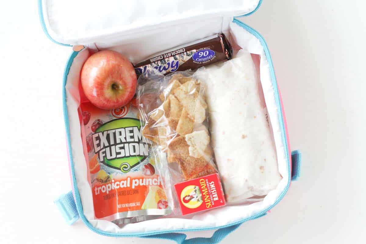 overhead view of lunchbox with wrap, drink, apple and snack