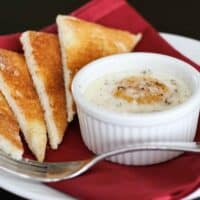 Single ramekin with baked egg over creamed spinach served with toast triangles.