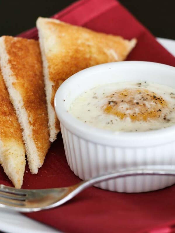 Single ramekin with baked egg over creamed spinach served with toast triangles.