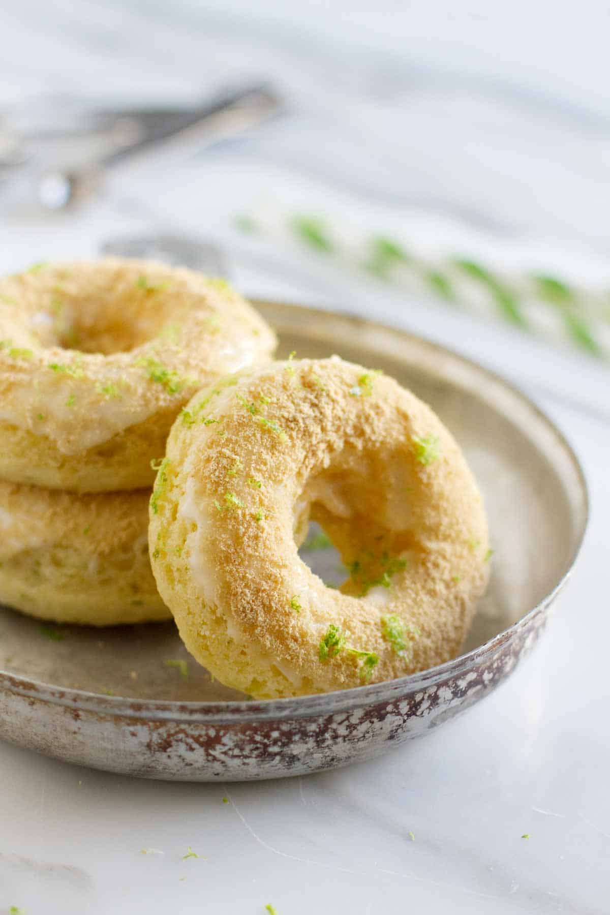 Baked Key Lime Pie Donuts - Baked donuts are made with a touch of key lime, then topped with a sweet key lime glaze and graham cracker crumbs for that key lime pie touch. Baked Key Lime Pie Donuts in a dish
