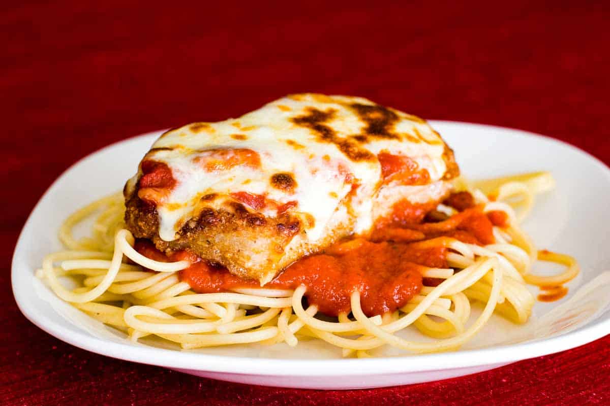 Boneless Pork Chops Parmigiana over spaghetti on a plate
